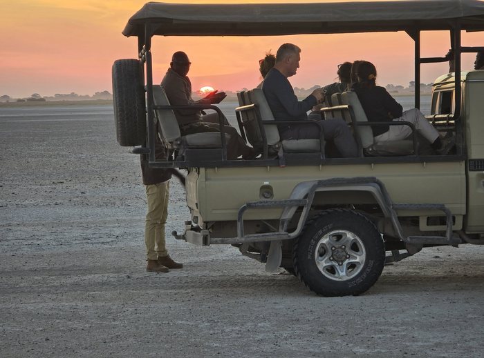 An open game-viewing vehicle on safari at sunset